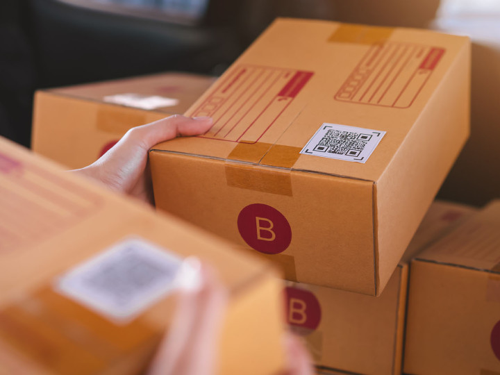 Startup small business, hand packing boxes for products to send to customers, working at the home office.
